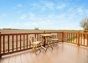 A wooden deck with a view of a plowed field and a clear sky. - Luxury 1 bedroom lodge. (Swinethorpe, Nr Lincoln)