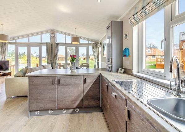 A modern kitchen with a large island, built-in appliances, and a view of the outdoors. - Luxury 1 bedroom lodge. (Swinethorpe, Nr Lincoln)