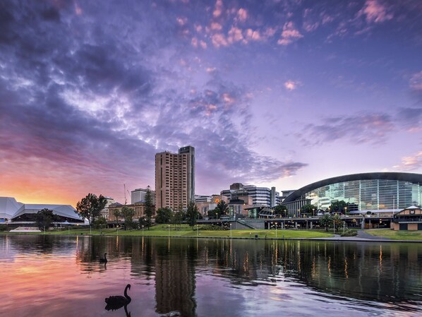 Stunning cityscape with a modern building and adjacent traditional structure, set against a serene body of water.