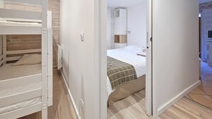 Quarto com beliche, uma cama de solteiro com cobertor verde e um guarda-roupa branco.
