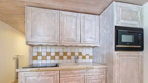 Cozinha com armários brancos, painel de azulejos e micro-ondas preto.