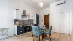 A modern kitchen with a dining area, including a table set for two, a chandelier, and an air conditioning unit. - GuestHost - Cozy renovated 52sqm apartment located on the first floor of a Milanese building with lift (with 4 steps to climb at the entrance). The property is located in a quiet and residential neighborhood, but at the same time a few steps from the Cen (Milano)