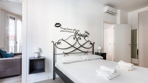 A bedroom with a bed, a nightstand with a lamp, a wall decoration, and a door. - GuestHost - Cozy renovated 52sqm apartment located on the first floor of a Milanese building with lift (with 4 steps to climb at the entrance). The property is located in a quiet and residential neighborhood, but at the same time a few steps from the Cen (Milano)