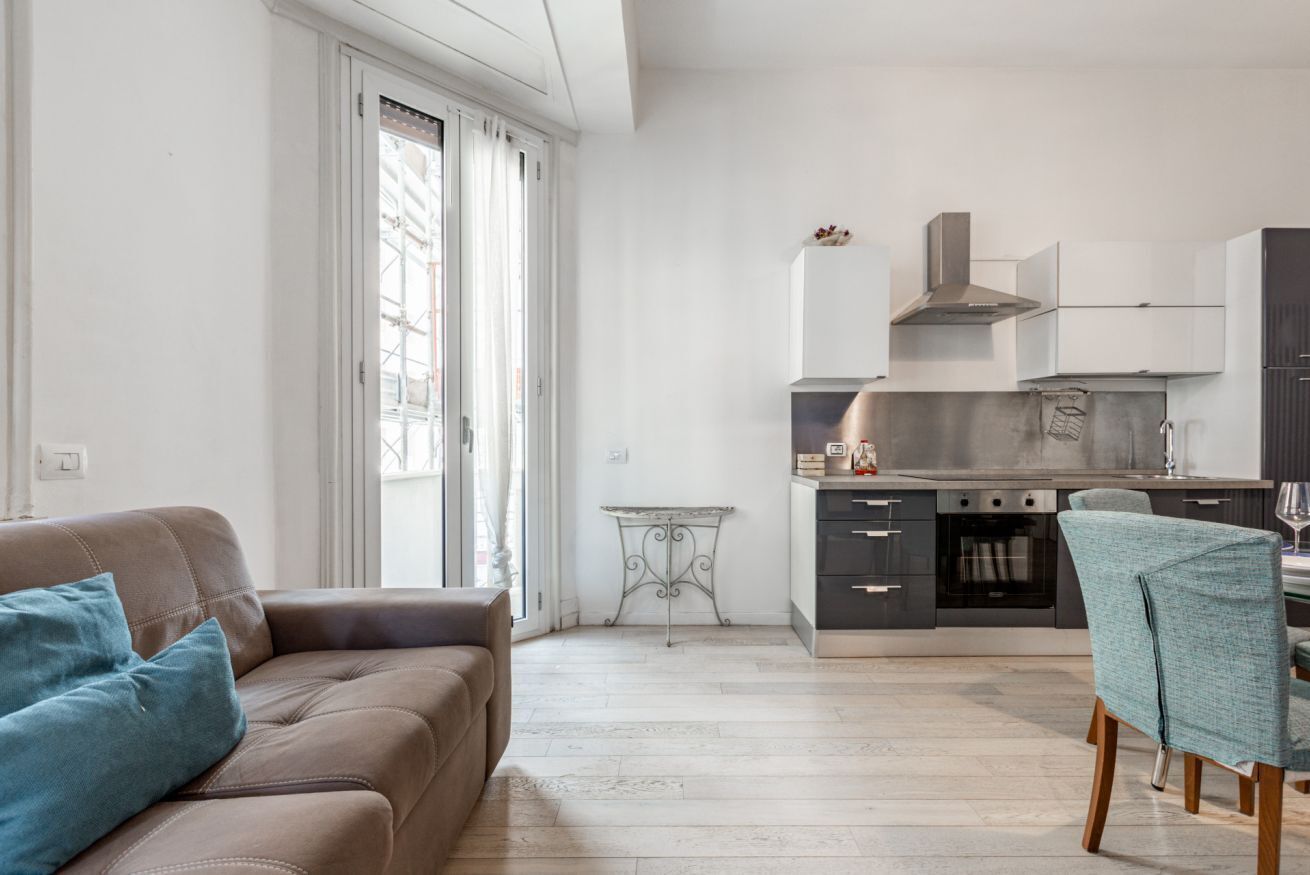 A modern kitchen with a dining area, a sofa, and a table.