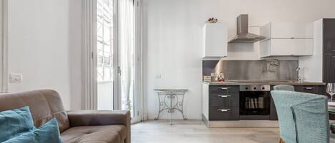 A modern kitchen with a dining area, a sofa, and a table.