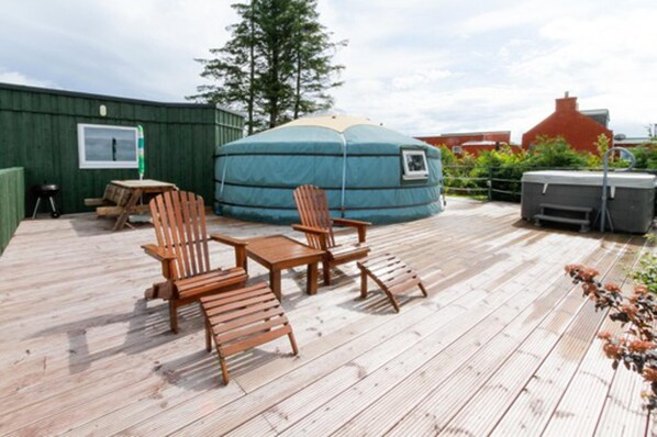 A wooden deck with a round blue tent, two wooden chairs, a small table, and a barbecue grill. - Green Yurt With Hot Tub - Sleeps 4, Parking & Pets (Turriff)