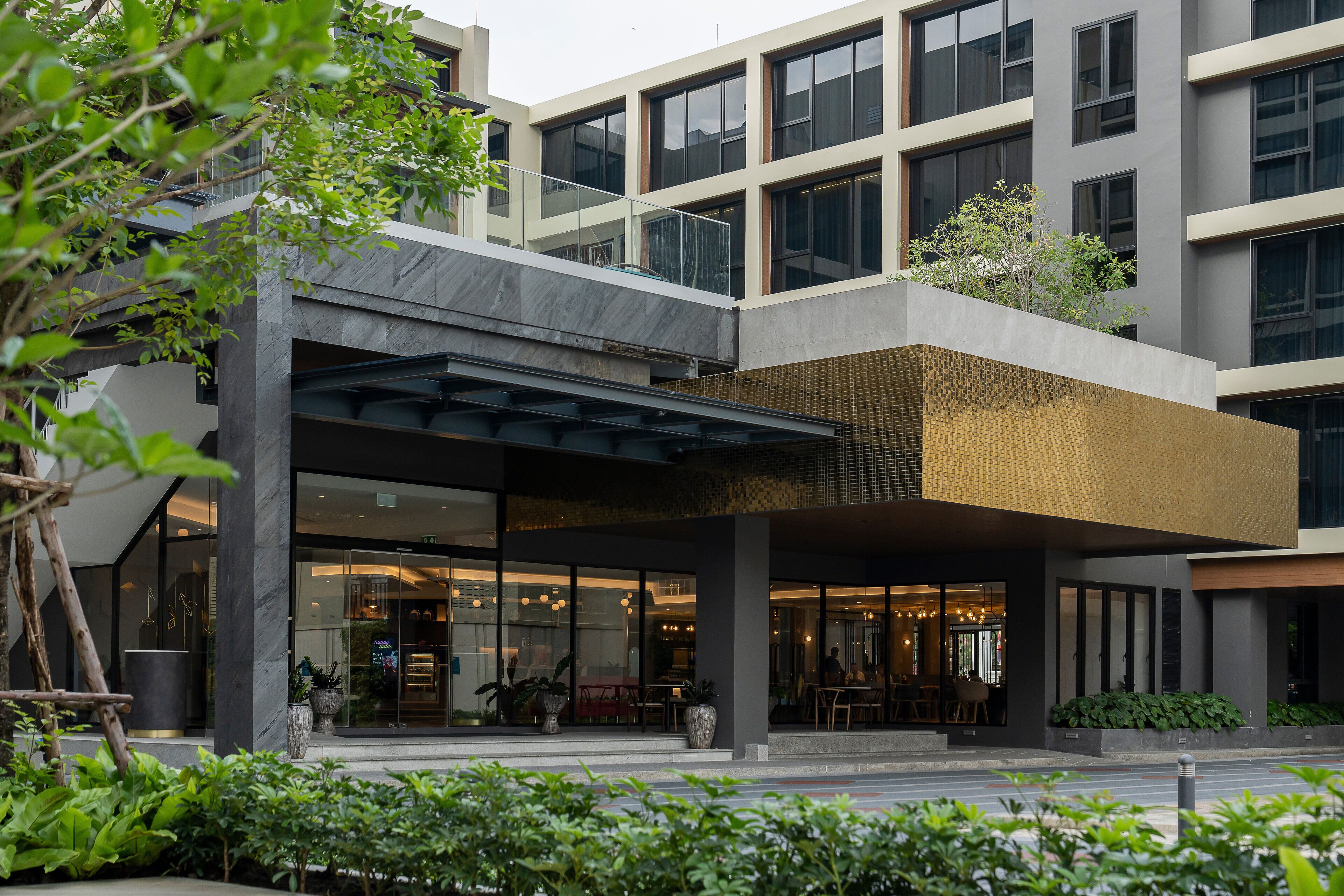 A modern building with a covered entrance, large windows, and outdoor seating.