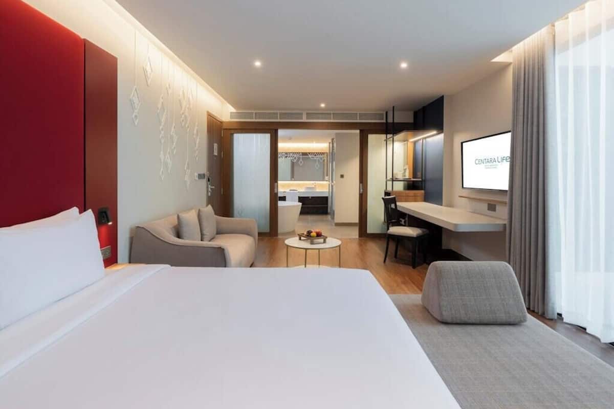 Ein Hotelzimmer mit einem Bett, einem Schreibtisch, einem Sessel, einer Couch und einem Fernseher.