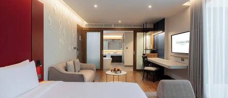 Una habitación de hotel con cama, escritorio, silla, sofá y televisor.