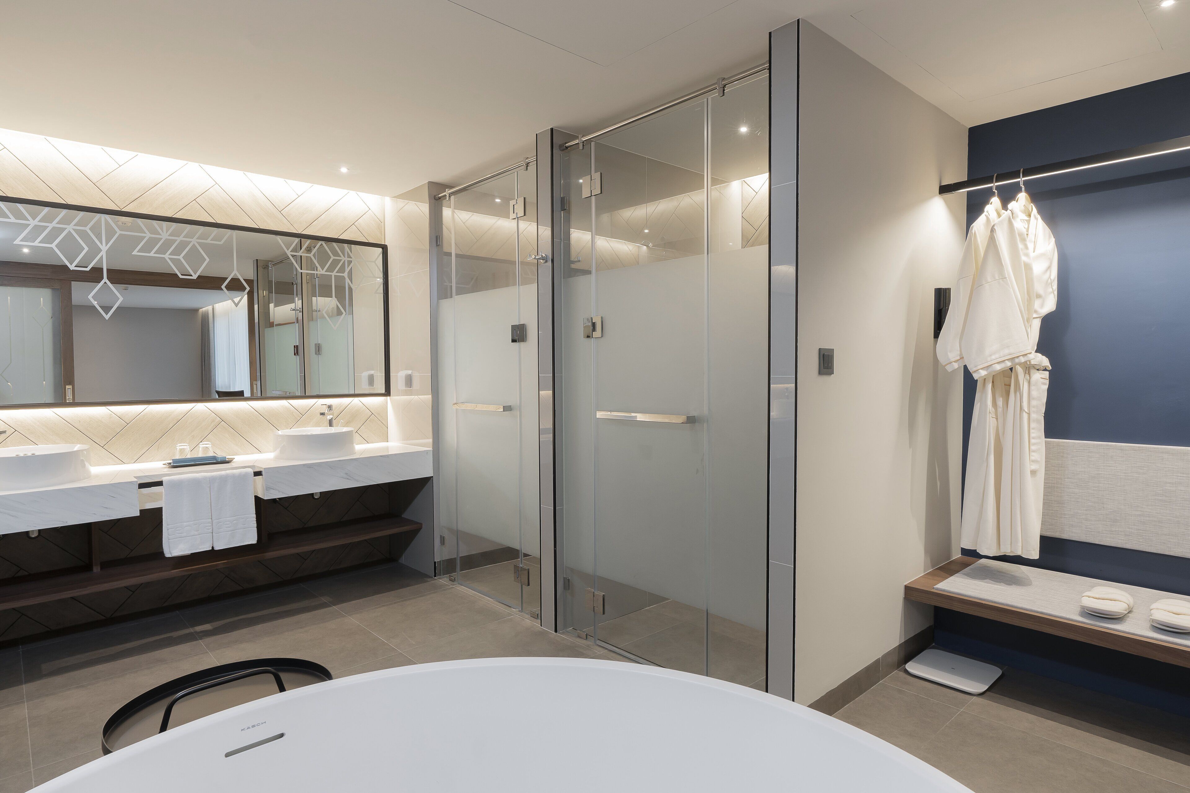 Un baño moderno con cabina de ducha de vidrio, un espejo grande y una bañera blanca.