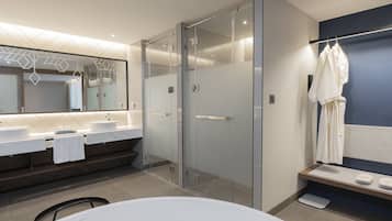 A modern bathroom with a glass shower enclosure, a large mirror, and a white bathtub.