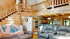 A spacious living area with a high ceiling, wooden beams, a staircase, leather sofas, and a rustic coffee table. - 🏕️  Angels Cabin, Firepit, Pool Table, LKT Mountain - Chattanooga Dwtn15 min!  (Lookout Mountain)