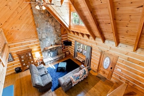 Ein Holzhütten-Interieur mit Kamin aus Stein, Holzwänden und einer gemütlichen Sitzecke.