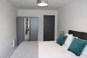 A bedroom with a bed, a wardrobe, a door, and a lamp.