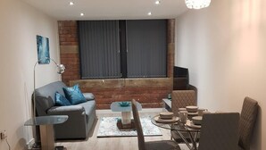 A modern living room with a grey sofa, a dining table with chairs, a floor lamp, and a large window with curtains. - Luxury 1-bed Apartment Bradford Free Parking (Bradford)