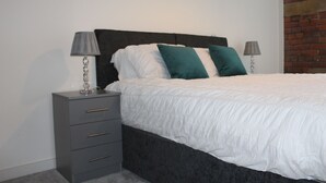 A bedroom with a bed, two bedside tables, and a brick wall. - Luxury 1-bed Apartment Bradford Free Parking (Bradford)