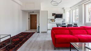A modern living room with a red sofa, a glass coffee table, and a patterned rug. - Cozy and bright 66sqm apartment located on the 6th floor of a building with lift (with a flight of stairs at the entrance to reach it).The accommodation is located in an exceptional position, just 300m from P.zza Gae Aulenti, famous for the wonderful vie (Milano)