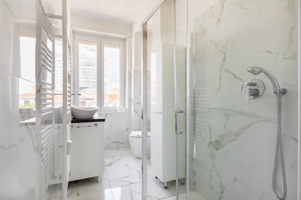 A modern bathroom with a glass shower enclosure, a white sink, and a toilet. - Cozy and bright 66sqm apartment located on the 6th floor of a building with lift (with a flight of stairs at the entrance to reach it).The accommodation is located in an exceptional position, just 300m from P.zza Gae Aulenti, famous for the wonderful vie (Milano)