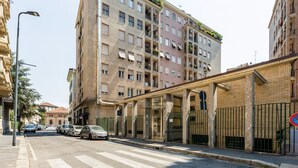 A street view with a pedestrian overpass, parked cars, and multi-story buildings. - Cozy and bright 66sqm apartment located on the 6th floor of a building with lift (with a flight of stairs at the entrance to reach it).The accommodation is located in an exceptional position, just 300m from P.zza Gae Aulenti, famous for the wonderful vie (Milano)