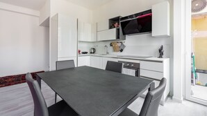 A modern kitchen with white cabinetry, a dining table, and chairs. - Cozy and bright 66sqm apartment located on the 6th floor of a building with lift (with a flight of stairs at the entrance to reach it).The accommodation is located in an exceptional position, just 300m from P.zza Gae Aulenti, famous for the wonderful vie (Milano)
