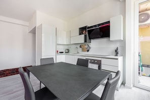 A modern kitchen with white cabinetry, a dining table, and chairs. - Cozy and bright 66sqm apartment located on the 6th floor of a building with lift (with a flight of stairs at the entrance to reach it).The accommodation is located in an exceptional position, just 300m from P.zza Gae Aulenti, famous for the wonderful vie (Milano)