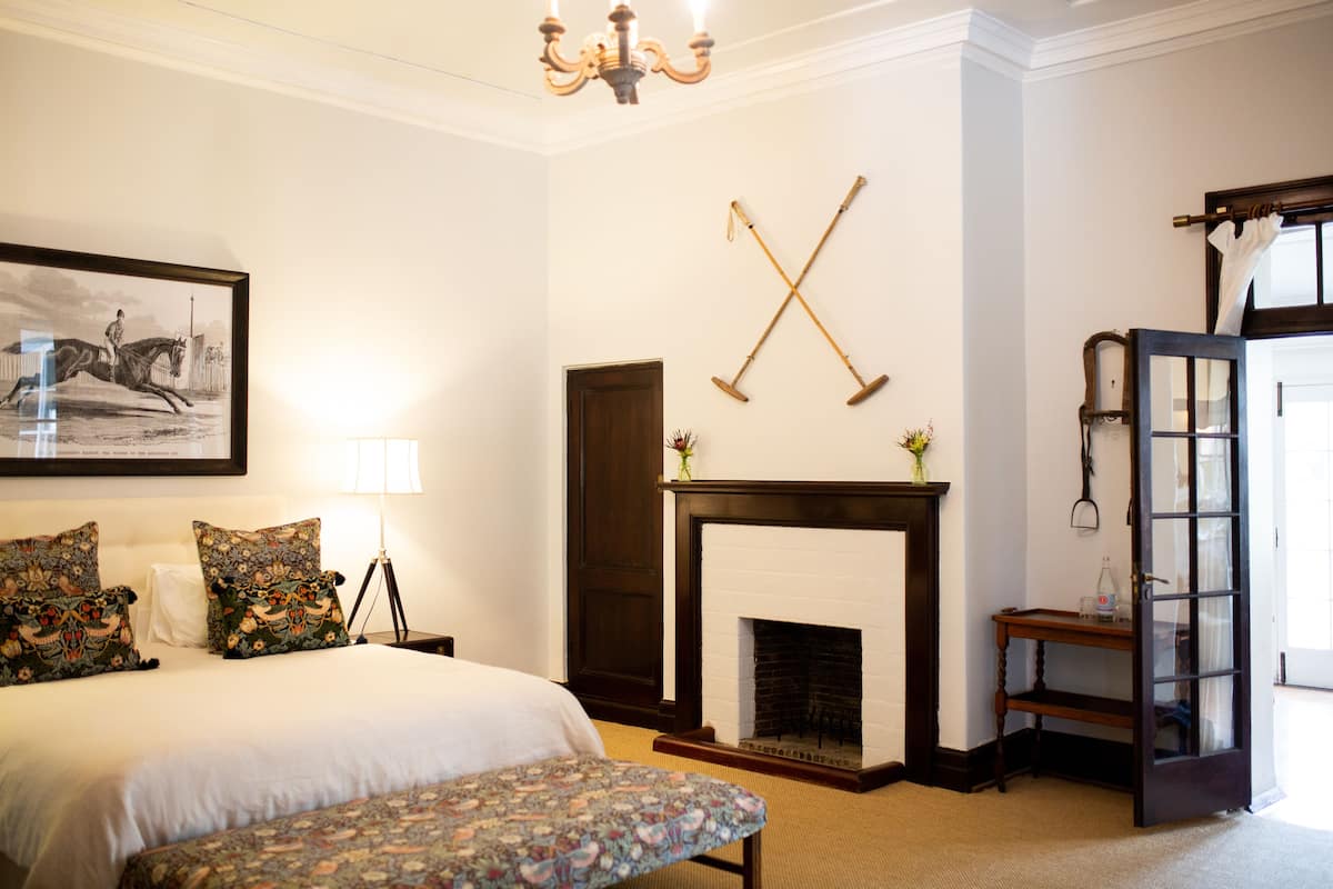 A bedroom with a bed, a bench, a fireplace, and a door.