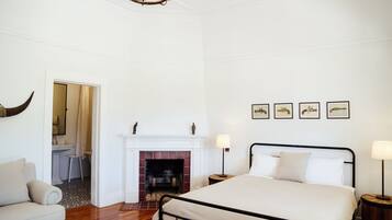 A bedroom with a bed, a fireplace, a chandelier, and framed pictures on the wall.