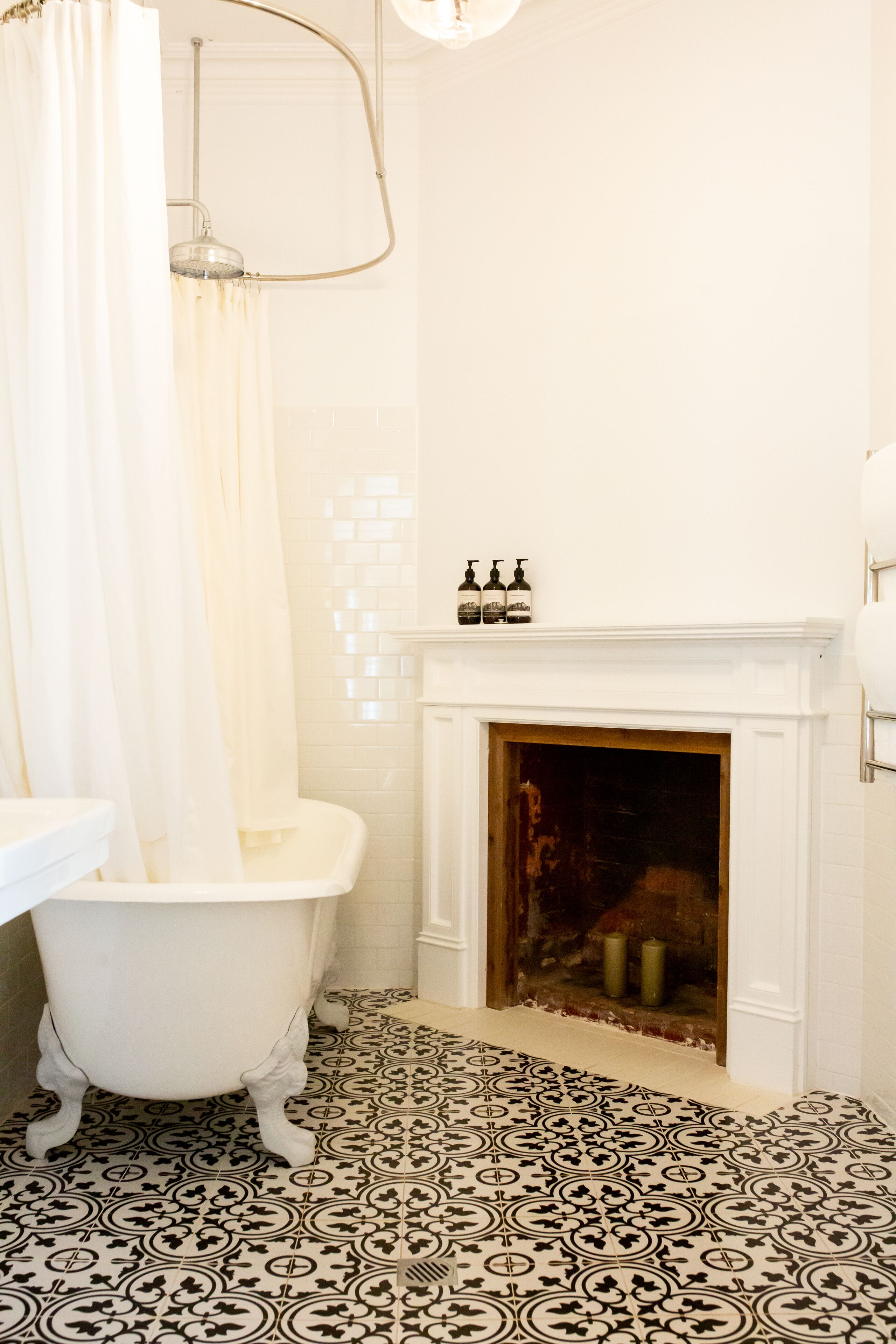 Un baño con una bañera blanca, ducha, suelo de baldosas y chimenea.