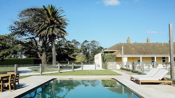 Una piscina al aire libre, sombrillas, sillones reclinables de piscina