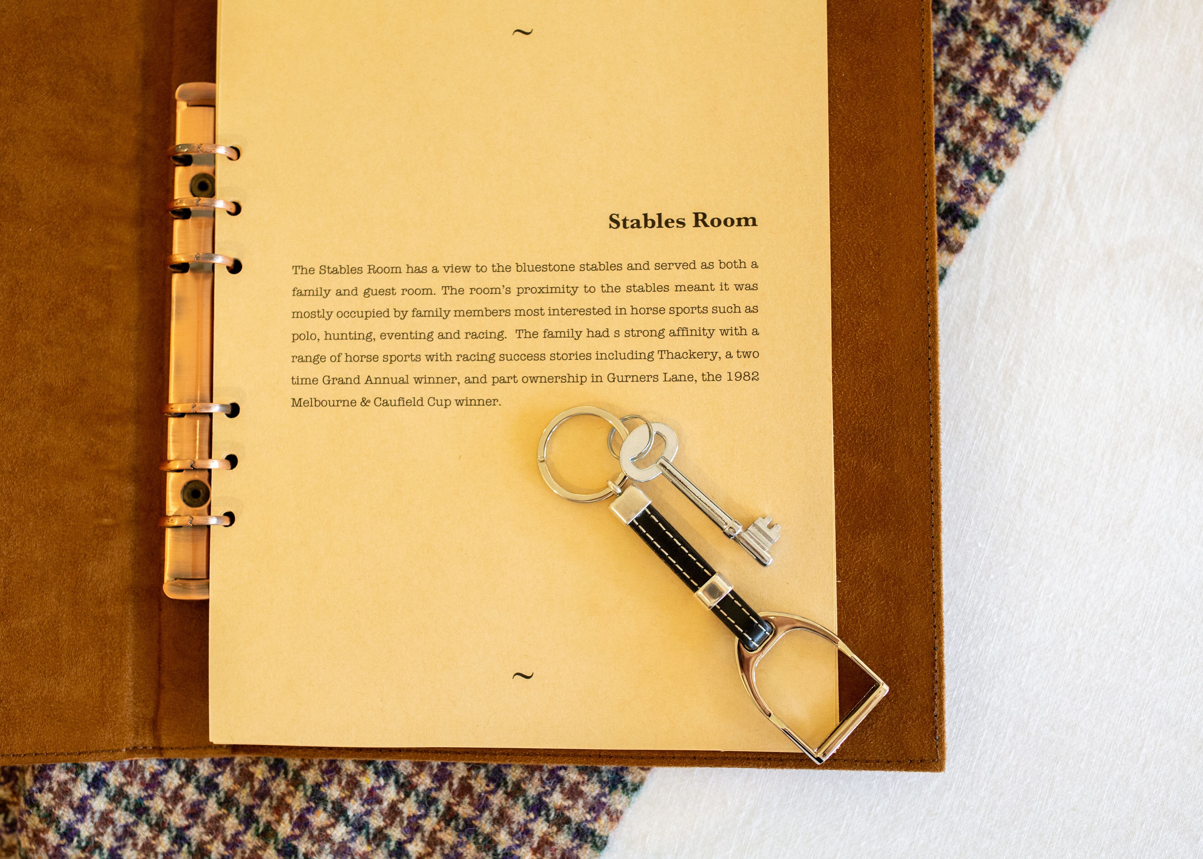 Une page intitulée « Salle des écuries » dans un livre à spirale, avec un porte-clés fixé à la page.