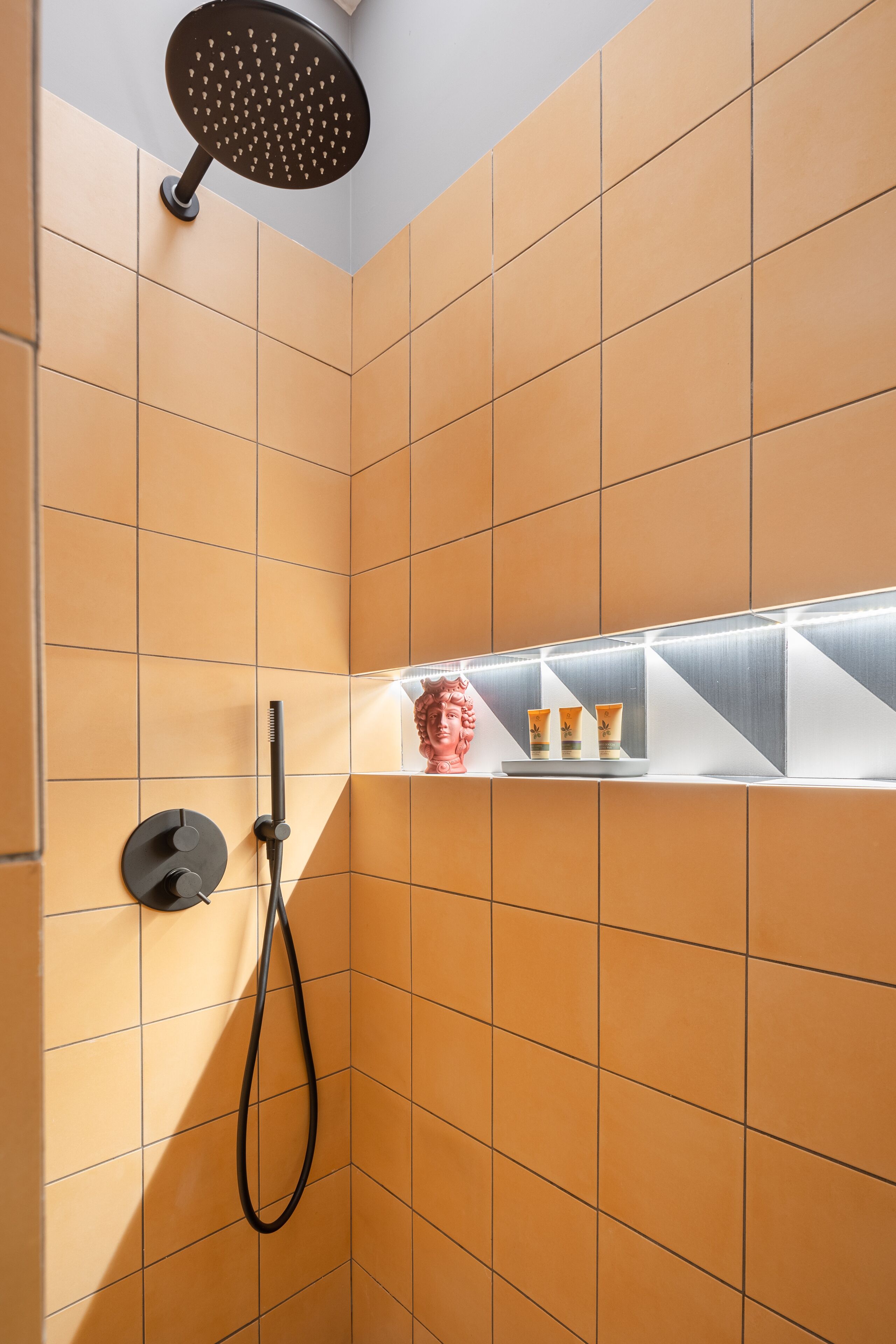 A shower with a handheld showerhead and a wall-mounted faucet.