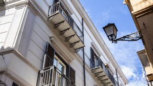 A building with multiple balconies, ornate iron railings, and a clear blue sky. - Vossia Luxury Rooms & Sicilian Living (Palermo)