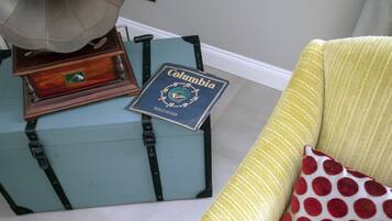 A vintage suitcase with a book titled "Columbia" on top, placed next to a yellow armchair with a red polka dot pillow.