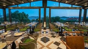 Un restaurant doté d’une terrasse, de grandes fenêtres et offrant une vue sur la mer.