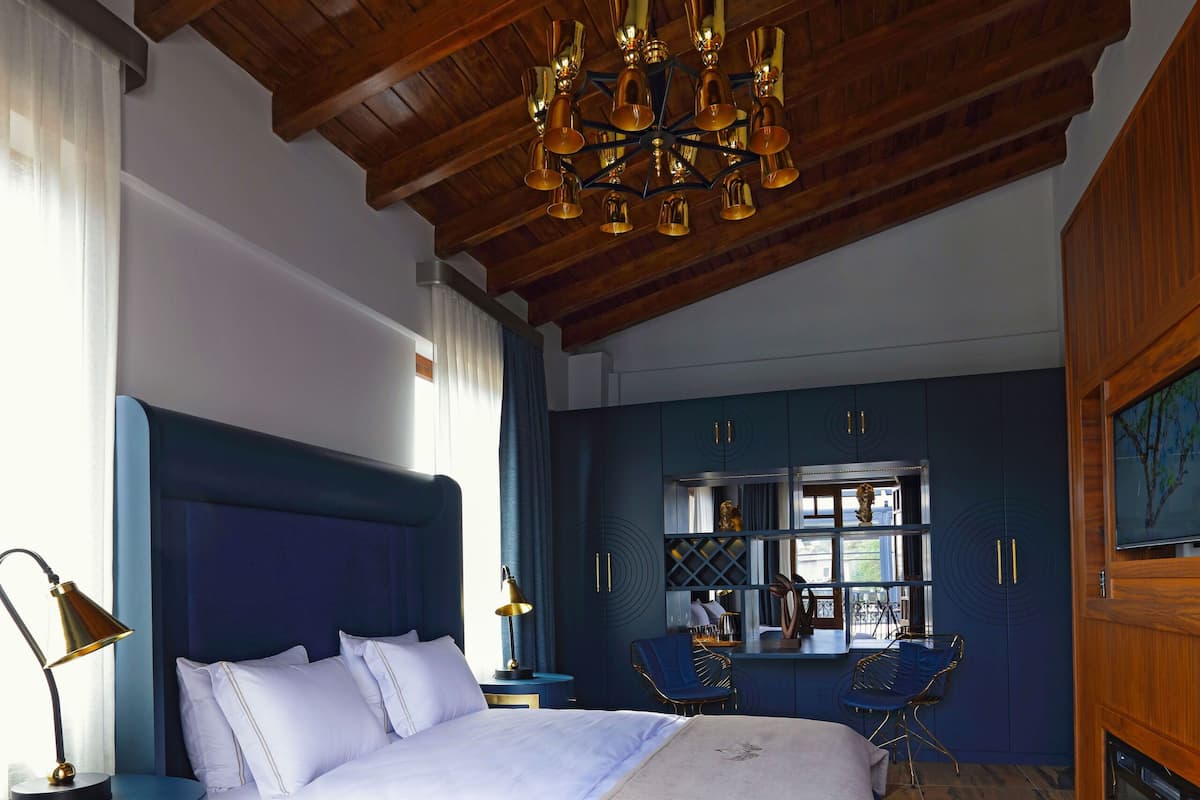 A bedroom with a large bed, wooden ceiling, and a chandelier.