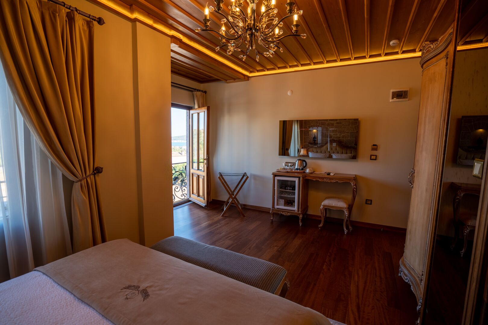 Quarto de hotel com cama, escrivaninha, cadeira, espelho e vista para o exterior.