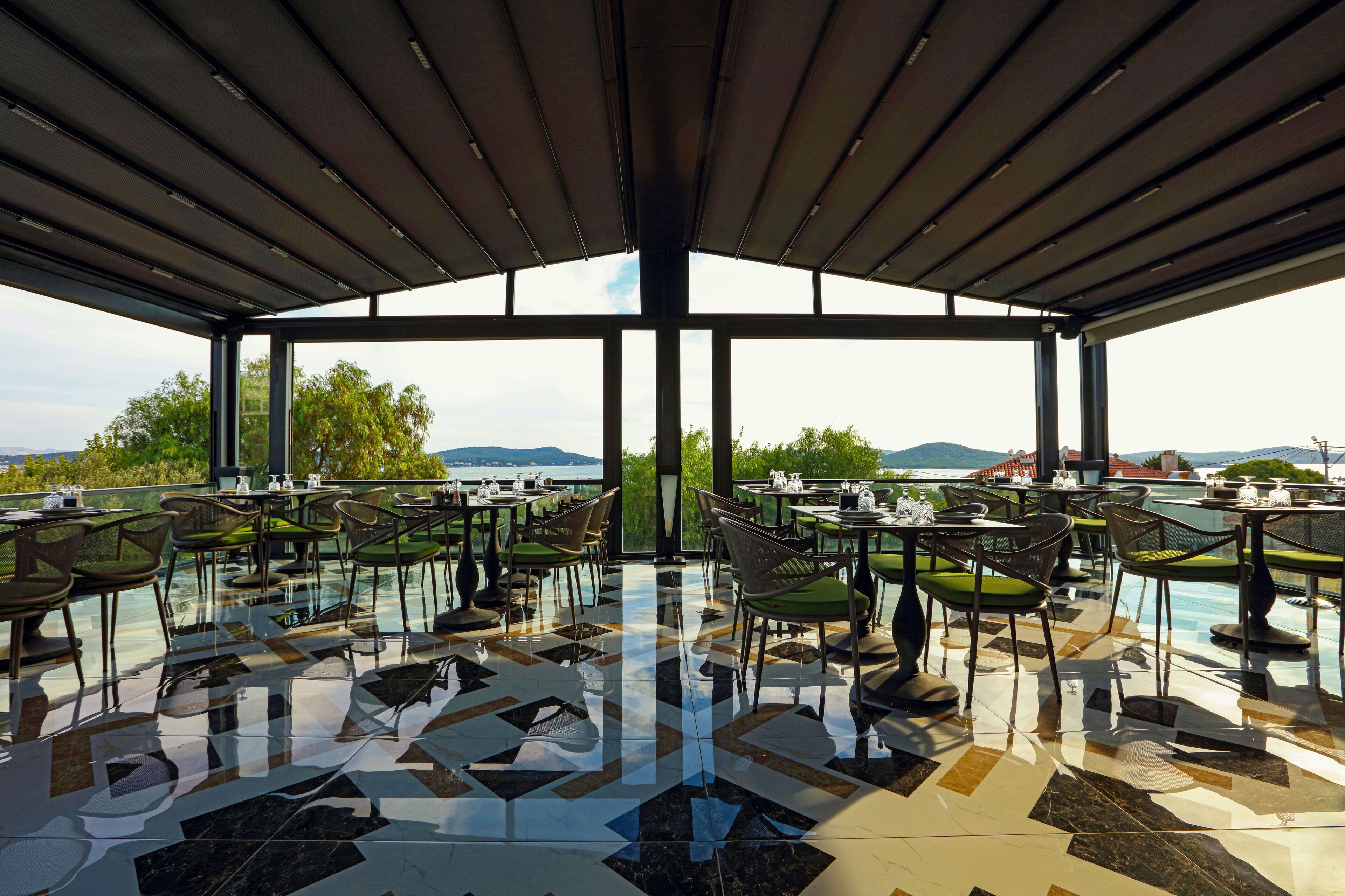 An outdoor dining area with a view of the sea and mountains.