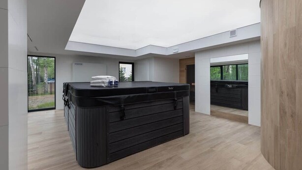 A modern spa room with a black massage table, a wooden cabinet, and a large window offering a view of the outdoors. - Intimate Apartment | SPA & Gym | 550 m to the beach (Miedzywodzie)