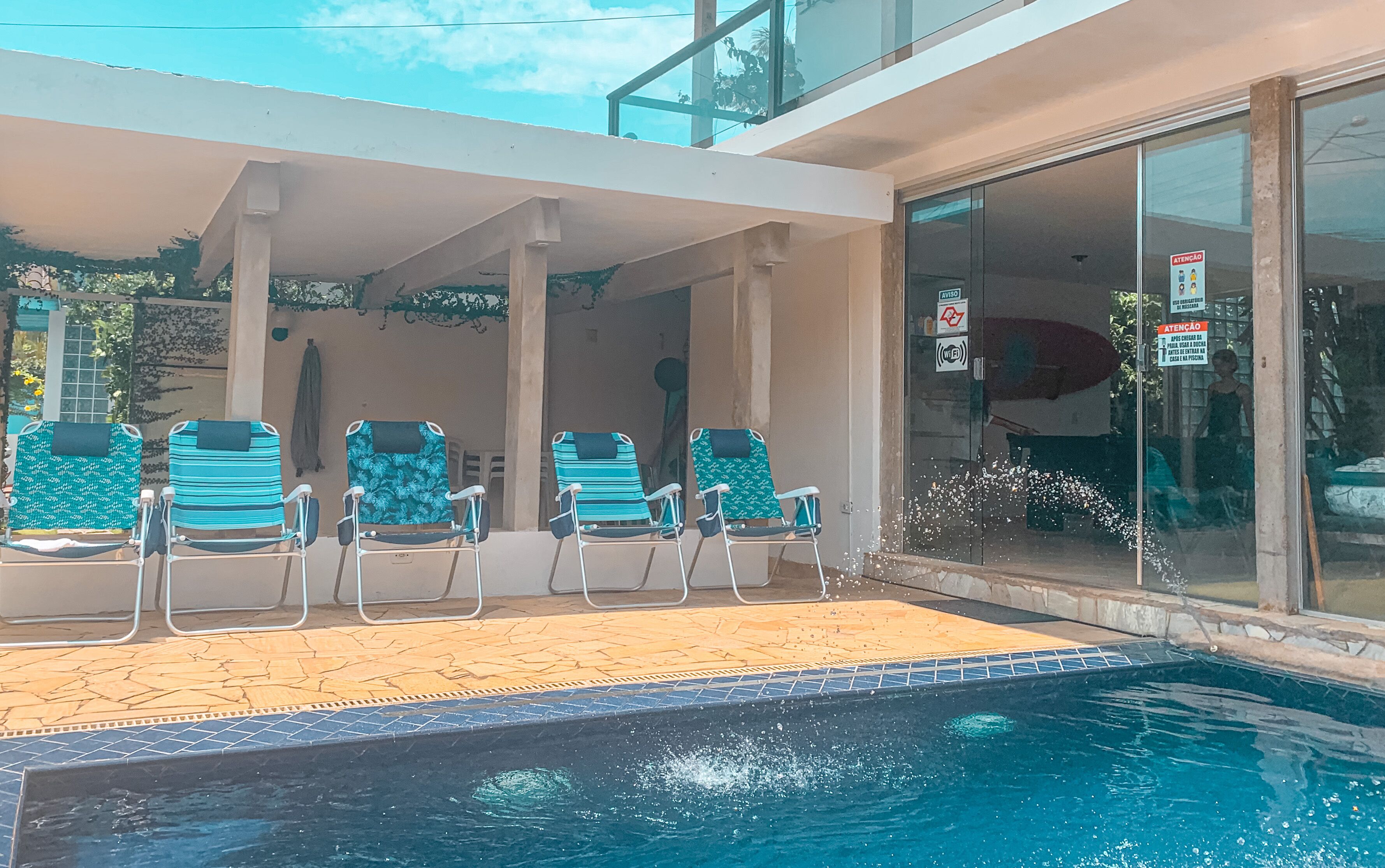 A poolside area with lounge chairs and a glass door entrance.