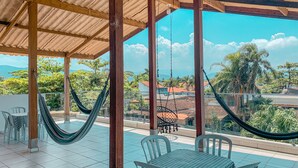 A covered outdoor seating area with a view of a residential neighborhood and mountains. - Pousada BellaSophia (Guarujá)
