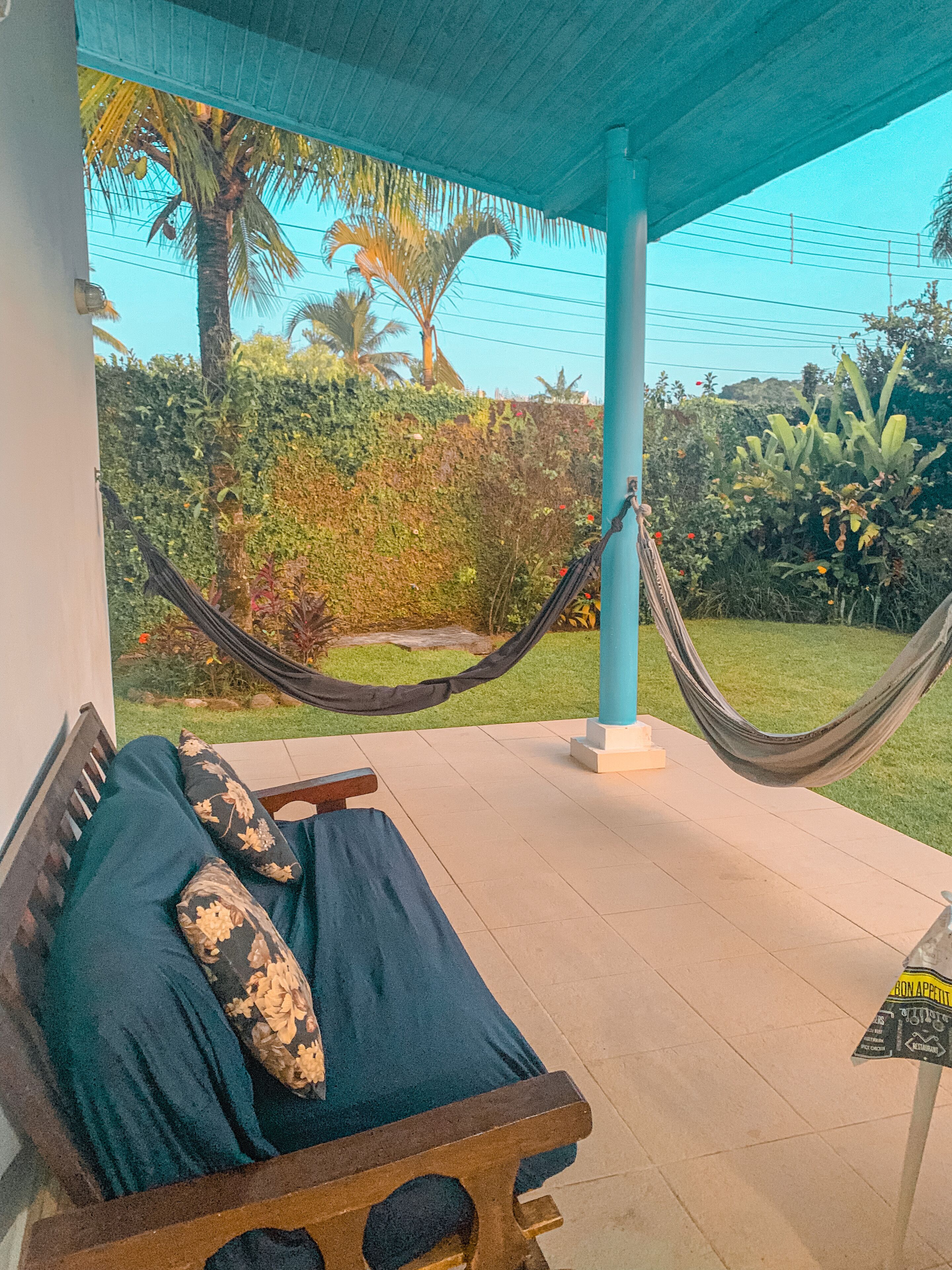 A hammock chair with floral cushions, a wooden bench, and a tiled floor.