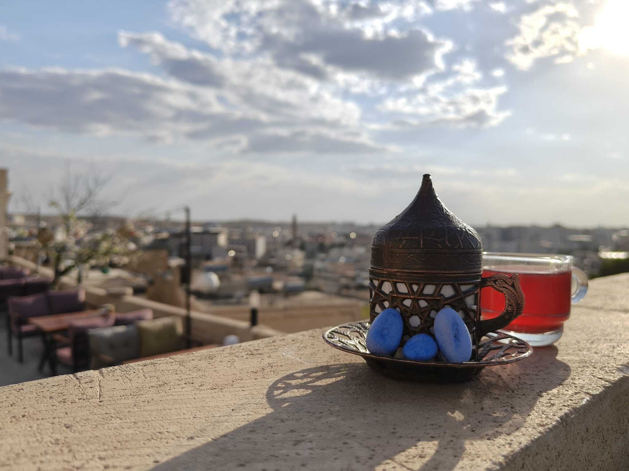 A traditional teapot and cup on a balcony overlooking a cityscape.