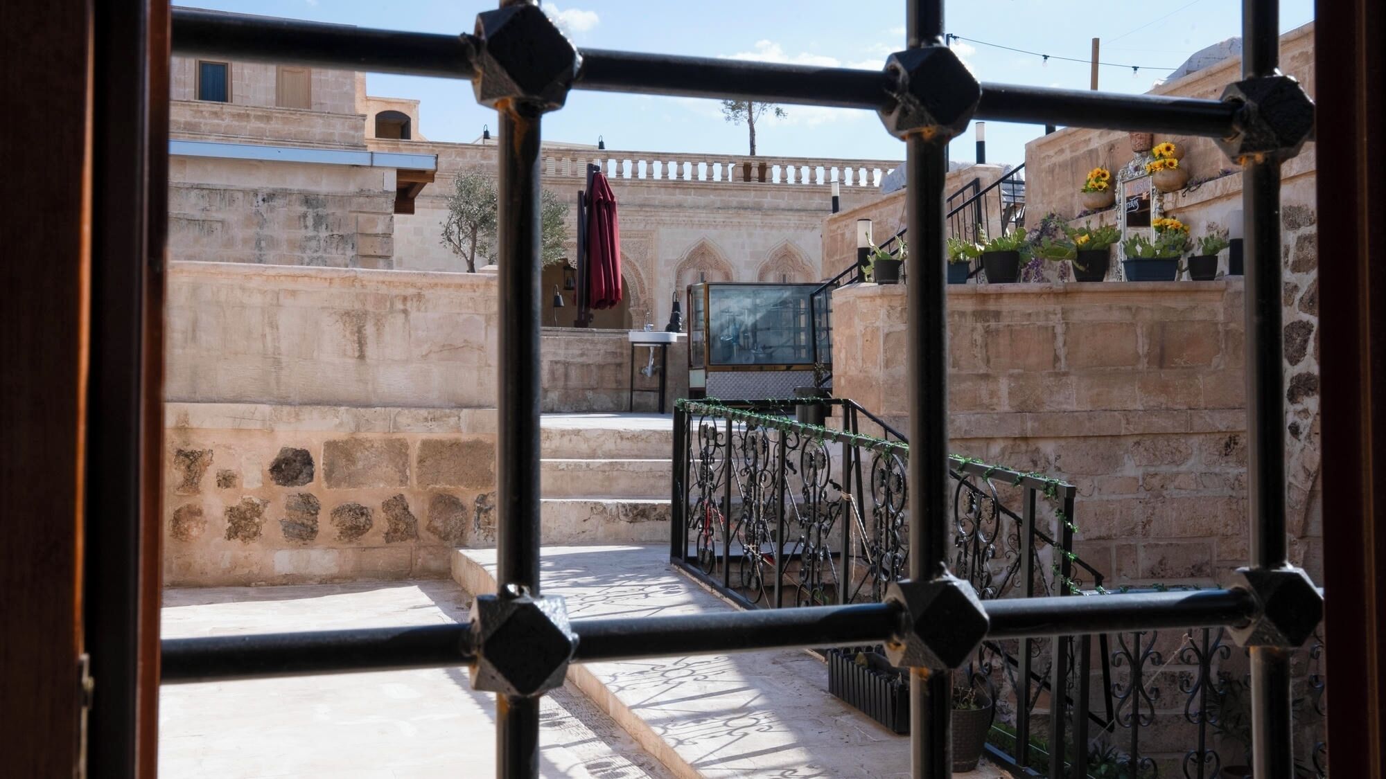 A courtyard with stone walls, a metal railing, and potted plants.