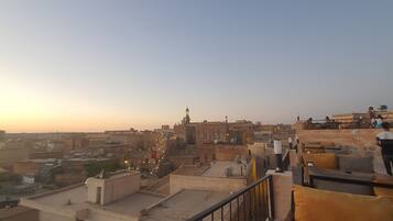 Une terrasse sur le toit offrant une vue sur le paysage urbain, avec des bâtiments et une mosquée dotée d’un minaret.
