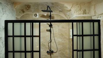 A shower enclosure with a glass door, a handheld showerhead, and a wall-mounted control panel.