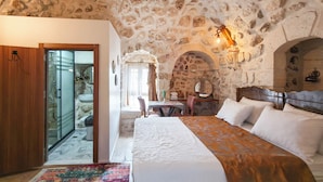 Un dormitorio con paredes de piedra, una cama, una puerta de madera y vistas al baño.