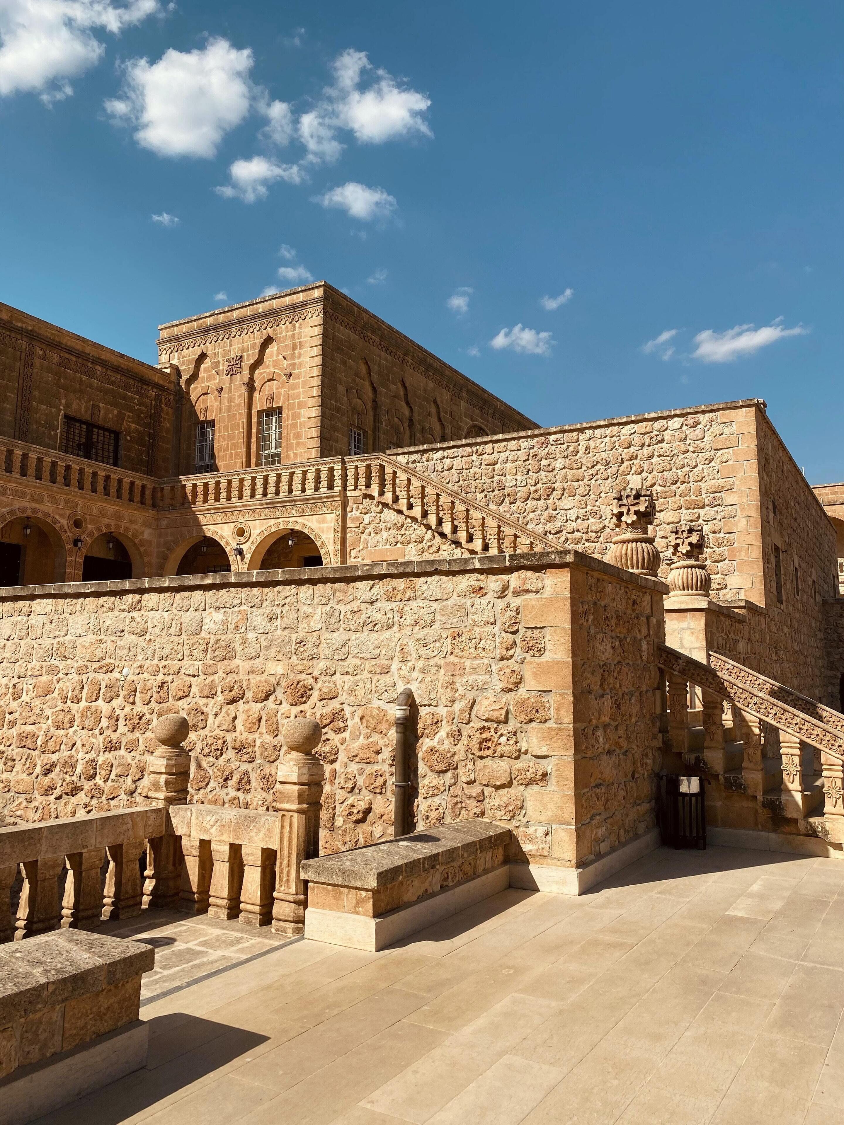 A historic building with stone walls, arched doorways, and a staircase leading to an upper level.