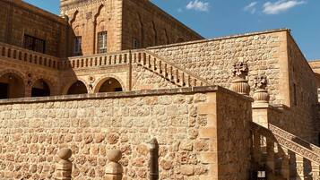 A historic building with stone walls, arched doorways, and a staircase leading to an upper level.