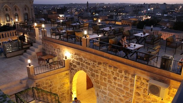 Una terraza en la azotea con muros de piedra, mobiliario exterior y vistas a la ciudad.