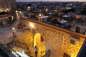 Una terraza en la azotea con muros de piedra, mobiliario exterior y vistas a la ciudad.